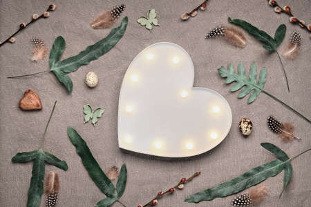 Jungle floral flat lay on linen textile. Bold tropical plant mix with dark red, burgundy and white gerbera flowers, feathers, quail eggs. Springtime floral flat lay with exotic fern leaves.の写真素材