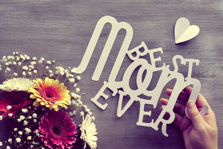 Mothers day greeting card design. Gerberas and white baby breath flowers on grey wood background....