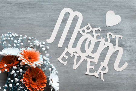 Mothers day greeting card design. Gerberas and white baby breath flowers on wood background. Flower arrangement, floral composition. Paper text Best Mom Ever. Happy Mothers day. Monochrome image.の写真素材