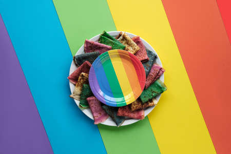 Rainbow pancakes, different color crepes. Spinach, beetroot powder, blue matcha and turmeric crepes. Colorful pancakes, flat lay on rainbow layered paper. Creative food,の写真素材