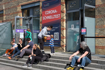 People sitting on the steps of coronavirus testing center in Berlin. Schnelltest means rapid test in...