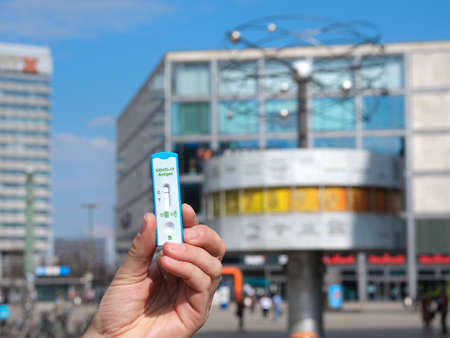 Hand hold express COVID-19 test on Alexanderplatz with shop and World Clock on the background. Schnelltest, quick corona test in German , is required for shopping.のeditorial素材