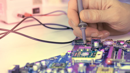 Closeup on the hands of tech checking motherboard. Technologiical background for your electronics...