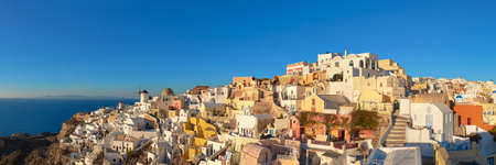 Sunset over Santorini island in Greece. Traditional church, apartments and windmills in Oia village on a sunset, panoramic imageの写真素材