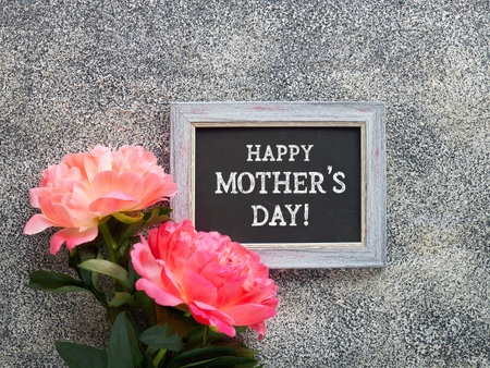 Happy Mothers Day greeting card. Peony flowers and blackboard with greeting text on textured stone background.の写真素材