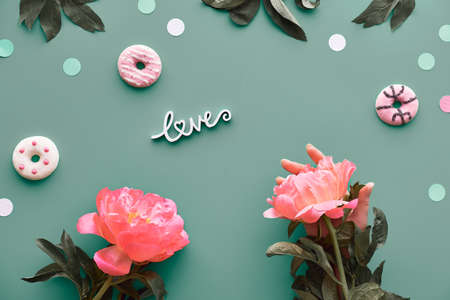 Peony greeting card, word love on grey background. Pink peony flowers, leaves and sweet donuts, doughnuts. Mothers day, birthday, romantic greeting arrangement, top view.の写真素材
