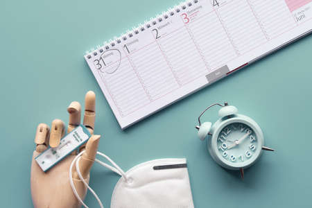 Week planner, chnelltest, rapid corona test in German language. Week planner calendar and pp2 medical face mask on mint green table. Test-to-go concept, flat lay, top view.の写真素材
