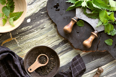 Stinging nettle, fresh herbs, herb knife on rustic wooden board.