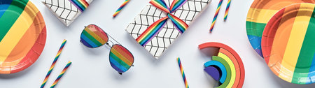 Banner, LGBTQ community pride month, birthday, rainbow concept flat lay. Gifts. Rainbow plates, sun glasses, drink straws. Flat lay, panoramic image, panorama. LGBT or birthday party decor.の写真素材