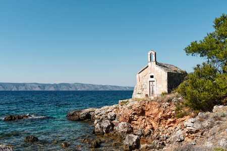 a lonesome old chapel near the seaside. red rocks and coniferous bushes, montains