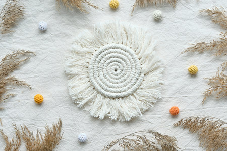 Sun shaped macrame pad. Textile flat lay with dry reeds, pampas grass and knitted cotton balls.