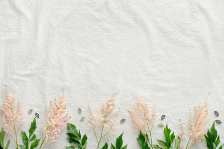 Natural Summer background with border of wild flowers. Copy-space, place for text. Flat lay on off white linen background with pale pink wild Prachtspiere flowers.の写真素材