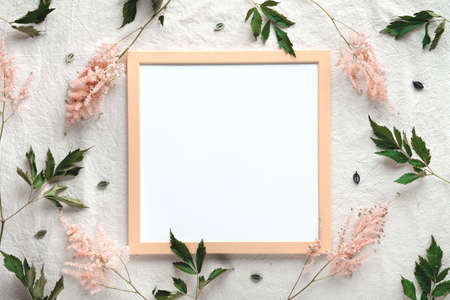 Natural summer wild flowers around pale orange wooden frame. Copy-space, place for text in frame. Flat lay on off white linen background with pale pink wild Prachtspiere flowers.の写真素材