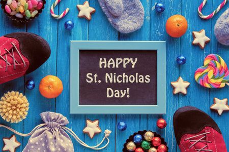 Text Happy St Nicolas Day on blackboard, chalk board. Traditional holiday in Germany and Western Europe on December 6. Various sweets, candy, cookies and rainbow heart. Top view on turquoise wood.の写真素材