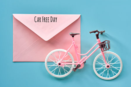 Car free day September 22. Toy model town bike on mint blue background. Text on pink paper envelope. Flat lay, top view, minimal retro vintage design.の写真素材