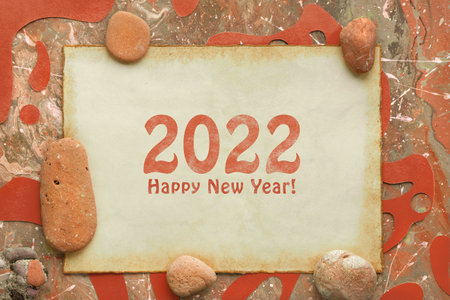 Text 2022 Happy New Year on aged paper. Abstract liquid acrylic background in orange, brown earth colors and natural stones. Simple monochromatic flat lay with muted colors and soft natural light.の写真素材
