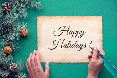 Traditional Christmas background with text Happy Holidays on aged parchment card. Hand holding...