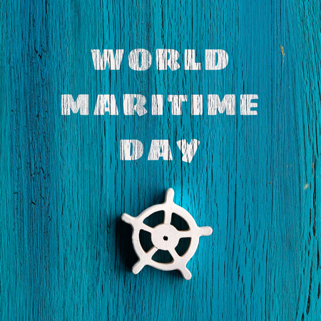 World Maritime Day text on grungy blue turquoise wooden background. Turquoise wood board with white steering wheel. Simple minimal arrangement, square composition.の写真素材