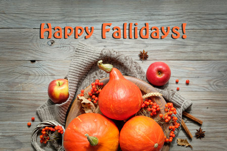 Happy Fallidays, text with orange Hokkaido pumpkins, rowan berry and Autumn decorations. Flat lay,...