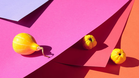 Autumn colors. Yellow pumpkin and quince fruits on bold red, orange, purple, violet layered paper....