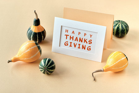 Autumn decorations, text Happy Thanksgiving on craft paper card. Natural decorative Fall pumpkins. Natural seasonal Fall composition in beige, green on cream paper background..の写真素材