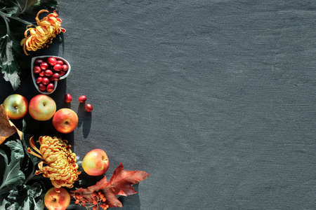 Orange chrysanthemum flowers, dry bunny tail grass and red oak leaves. Autumn decorations, top view with copy-space. Flat lay on dark textile.の写真素材