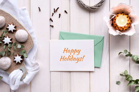 Winter greeting card in hand. Text Happy Holidays. Eucalyptus twigs, candle in pomander ball.の写真素材