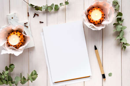 Wintertime notebook mockup with eucalyptus twigs, natural orange tea light and gingerbread cookies.の写真素材