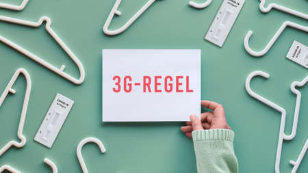 White plastic hangers, hand holding white paper with copy-space. Top view flat lay on trendy pastel green neo mint background, creative minimalism. Sale concept, shopping online, great prices.の写真素材