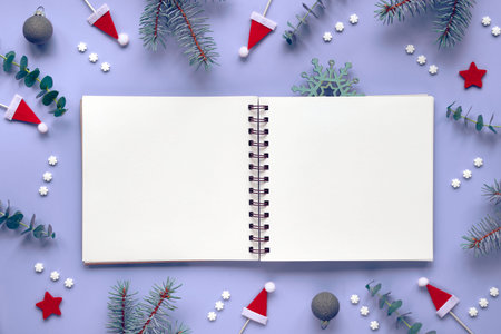 Mockup with blank notebook. Eucalyptus, fir twigs, red Santa hats and stars. Sugar snowflakes and...