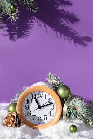 Christmas decor, wood alarm clock on purple very peri background. Sunshine, snow and fir twigs....