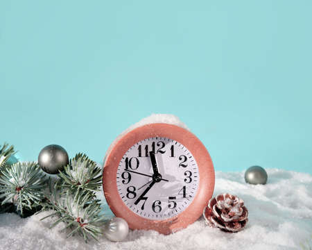 Christmas decor, wood alarm clock on mint blue background. Sunshine, snow and fir twigs. Sunlight, strong shadows. Xmas creative greeting card design, copy-space.の写真素材
