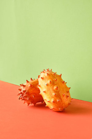 Dragon fruit, pitahaya. Close-up on two fruits on two color paper background. Vibrant orange and...