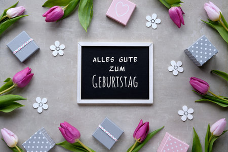 Text Alles gute zum Geburtstag means Happy Birthday in German. Spring flat lay with gift boxes,...