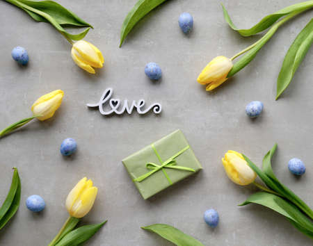 Easter, springtime flat lay with wrapped gift box, yellow tulips and blue quail eggs. Spring holiday background with natural flowers. Easter, Mothers day greeting card arrangement.の写真素材