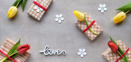 Panoramic banner Spring flat lay, light grey stone background. Gifts wrapped in craft paper, word...