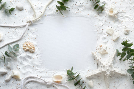 Sand frame with eucalyptus, seashells. starfish, cord.Monochromatic off white flat lay, copy-space.