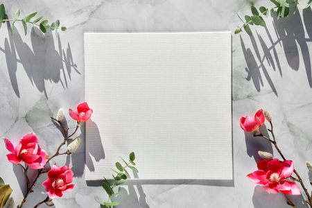 Springtime mockup with blank square canvas and Spring decorations. Pink magnolia twigs, eucalyptus.
