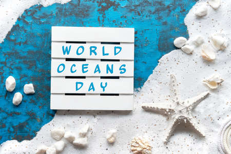 World Oceans Day text. Background with white sand on turquoise blue texture with shells, starfish.の写真素材