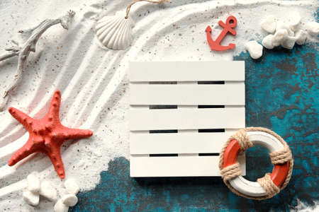 Sand and sea background. White sand on turquoise blue with pebbles, red starfish, anchor, safe ring.の写真素材