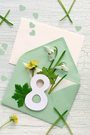 March 8, International Womens Day. Greeting envelope with number 8, snowdrop flowers, hearts on off white table.の写真素材