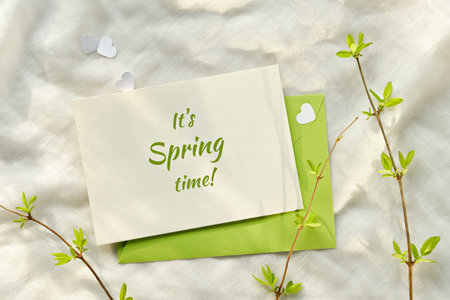 Text Its Spring time on card. Spring background with green envelope, white paper card, green leaves