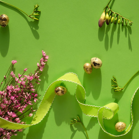 Spring Easter background in shades of green. Pink flowers amd quail Easter eggs on square paper...