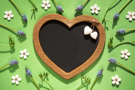 Spring flat lay on light green with fresh freesia flowers and wooden floral decorations. Text space...