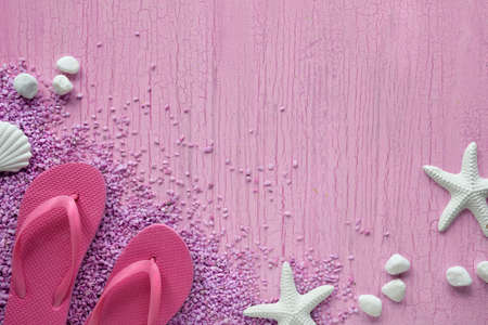 Summer by the sea. Pink rubber flip-flops, slippers on pebbles with starfish and pebbles, studio concept. Pink textured background, copy-space.の写真素材