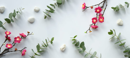Red plum flowers on twigs, fresh eucalyptus leaves. Chinese new year design banner. Top view on off...