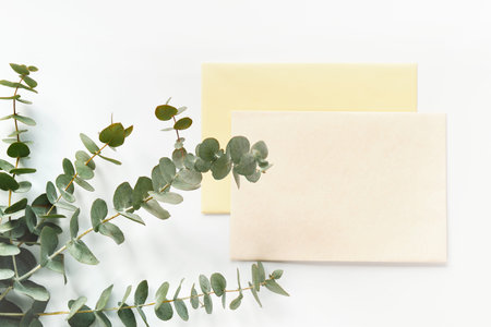 Fresh eucalyptus and blank card with envelope. Wooden heart trinket with white enamel. Top view on...