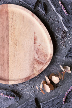 Orange wooden tray. Layered flat stone background with broken pieces of granite, dry eucalyptus.