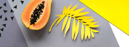 Background with papaya, exotic fruit and leaves. Illuminating Yellow and Ultimate Gray, colors of the year 2021. Layered paper top view with circles and palm leaf silhouettes, paper decorations.の写真素材