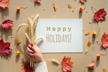 Autumn frame, caption greeting text Happy Holidays. Natural Fall leaves, wheat ears in hand with...